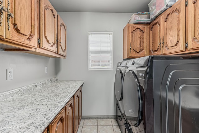 laundry area with cabinet space, baseboards, washing machine and dryer, and light tile patterned floors
