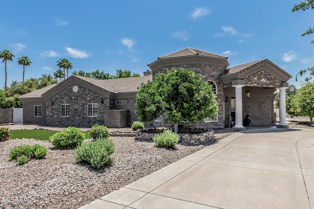 single story home featuring concrete driveway, a tile roof, and stone siding