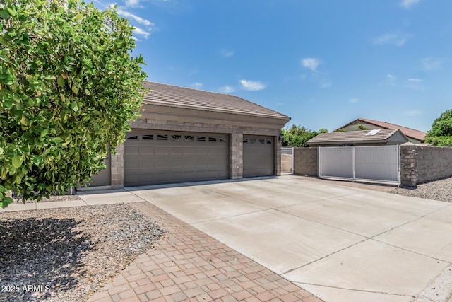garage with concrete driveway, fence, and a gate