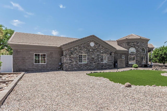 view of front of property with a front yard, a tile roof, and stone siding