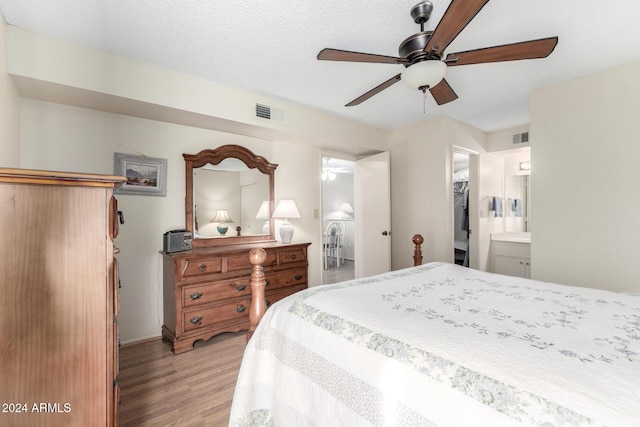 bedroom featuring visible vents, a spacious closet, a textured ceiling, light wood-type flooring, and a closet