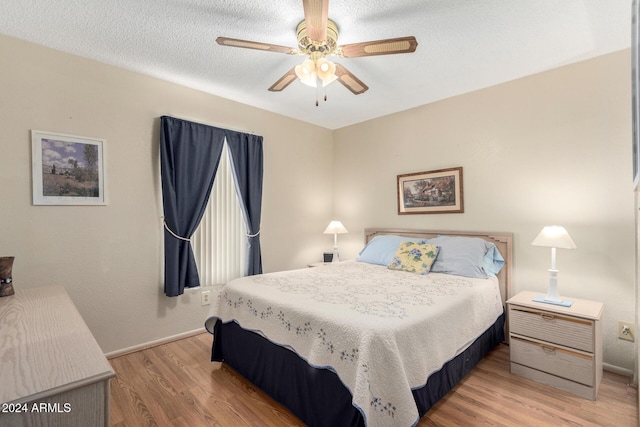 bedroom featuring light wood-style floors, a textured ceiling, and baseboards