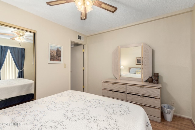 bedroom with visible vents, a ceiling fan, wood finished floors, a textured ceiling, and a closet