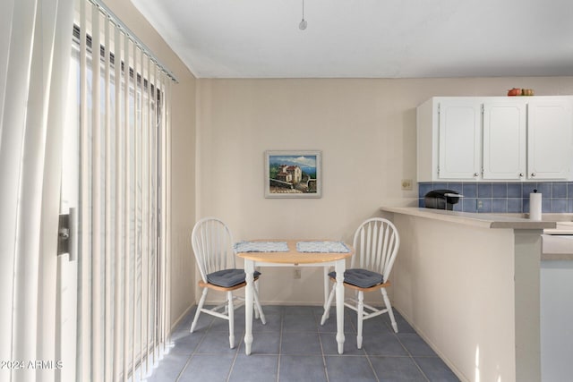 dining area featuring baseboards, breakfast area, and dark tile patterned flooring