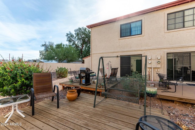 wooden deck with outdoor dining area, fence, and area for grilling