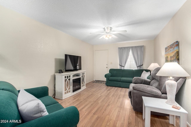 living area with a textured ceiling, ceiling fan, and light wood-style flooring