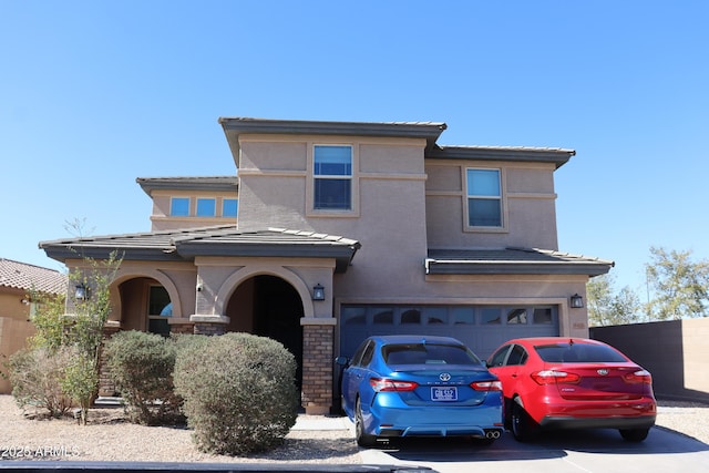 view of front facade featuring a garage, concrete driveway, a tiled roof, and stucco siding