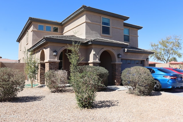 prairie-style house featuring a garage, stone siding, and stucco siding