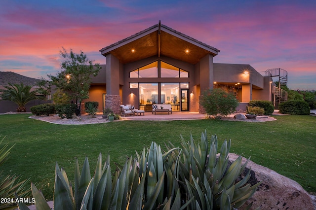 back house at dusk with a yard, outdoor lounge area, and a patio