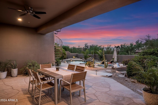 patio terrace at dusk with ceiling fan and a fenced in pool