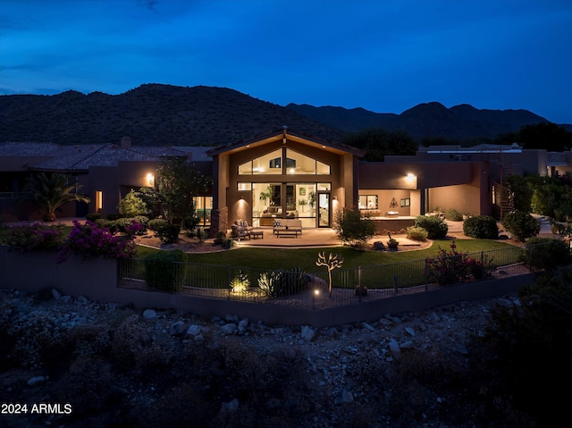 back house at night with a yard, a patio area, and a mountain view