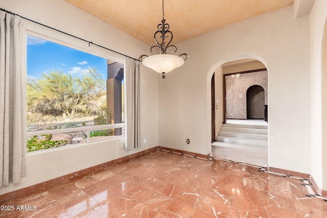 unfurnished room with baseboards and arched walkways