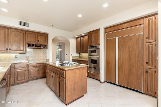 kitchen with visible vents, a center island, arched walkways, appliances with stainless steel finishes, and decorative backsplash