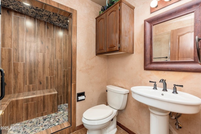 bathroom featuring baseboards, tiled shower, and toilet