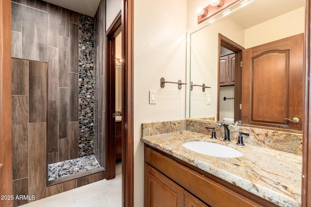 full bath featuring tile patterned flooring, vanity, and a tile shower