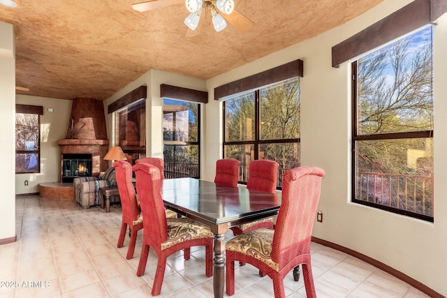 dining area with a fireplace, baseboards, and ceiling fan