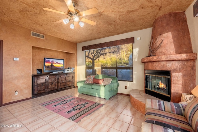 living room with tile patterned flooring, visible vents, baseboards, ceiling fan, and a fireplace