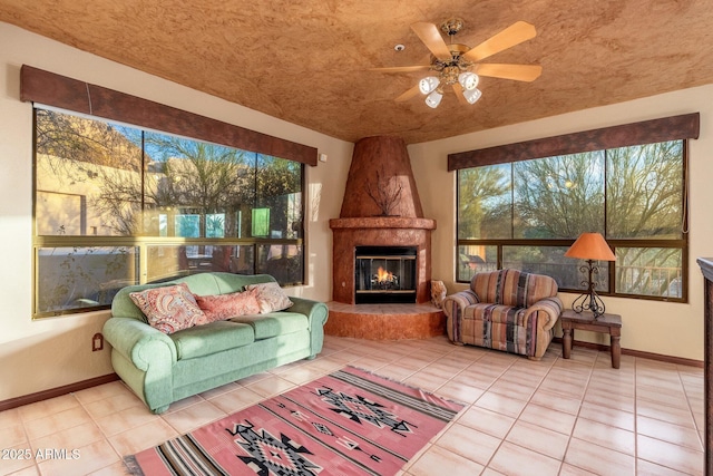 tiled living area featuring baseboards, ceiling fan, and a fireplace