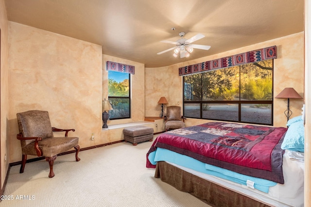 carpeted bedroom with multiple windows, a ceiling fan, and baseboards