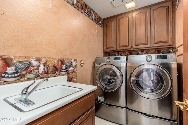 washroom with a sink, cabinet space, separate washer and dryer, and a textured wall