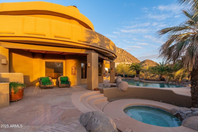 outdoor pool with a patio area, a mountain view, and an in ground hot tub