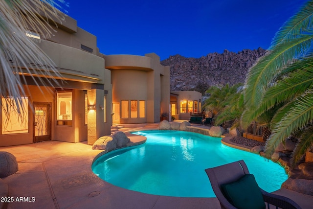 pool at twilight featuring a patio area and an outdoor pool