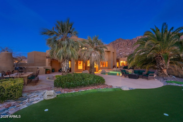 exterior space featuring stucco siding, an outdoor hangout area, a yard, and a patio area