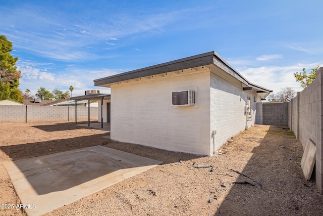 view of side of home with a wall mounted air conditioner and a patio area