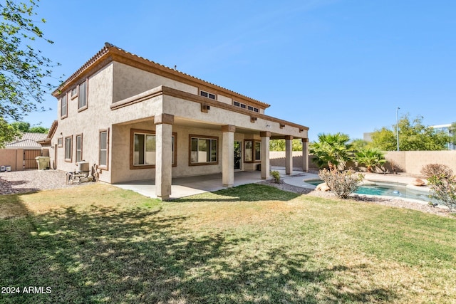 rear view of property featuring a yard, a patio area, and a fenced in pool