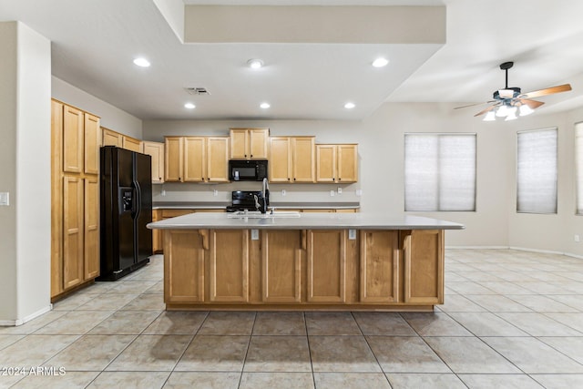 kitchen with ceiling fan, black appliances, light tile patterned floors, and a kitchen island with sink