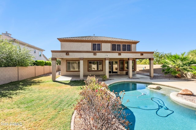 rear view of property featuring a yard, a patio area, and a fenced in pool