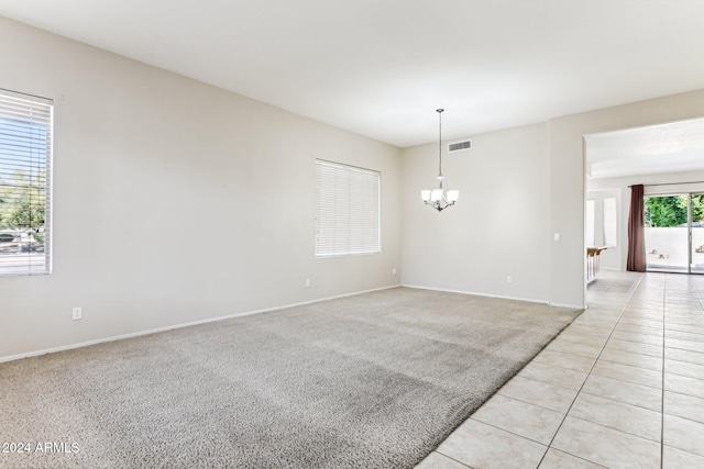 unfurnished room featuring a notable chandelier and light tile patterned floors