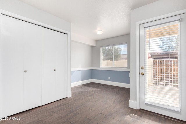 interior space featuring a textured ceiling, wood finished floors, a closet, and baseboards