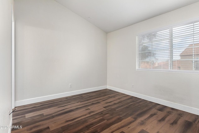 empty room with dark wood finished floors, baseboards, and vaulted ceiling