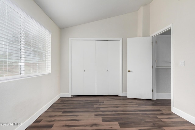 unfurnished bedroom featuring a closet, wood finished floors, baseboards, and vaulted ceiling