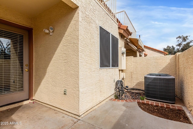 doorway to property with a patio, fence, central AC, and stucco siding