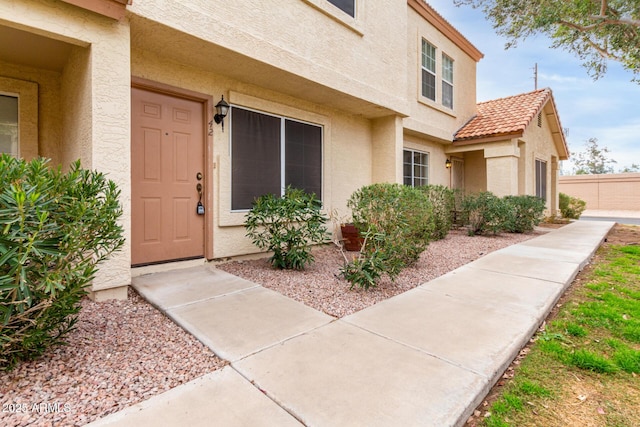 doorway to property with fence and stucco siding