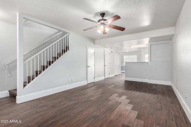 unfurnished living room featuring baseboards, ceiling fan, dark wood finished floors, stairway, and a textured ceiling