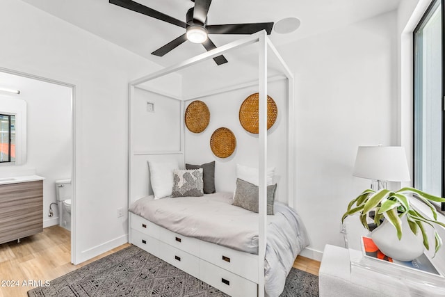 bedroom with baseboards, multiple windows, light wood-type flooring, and connected bathroom