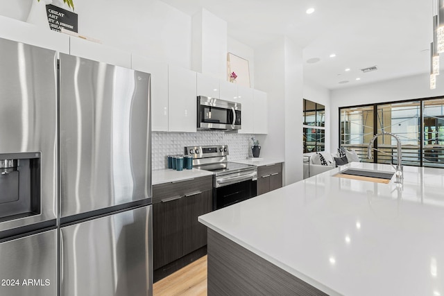 kitchen featuring modern cabinets, light countertops, a sink, white cabinets, and stainless steel appliances
