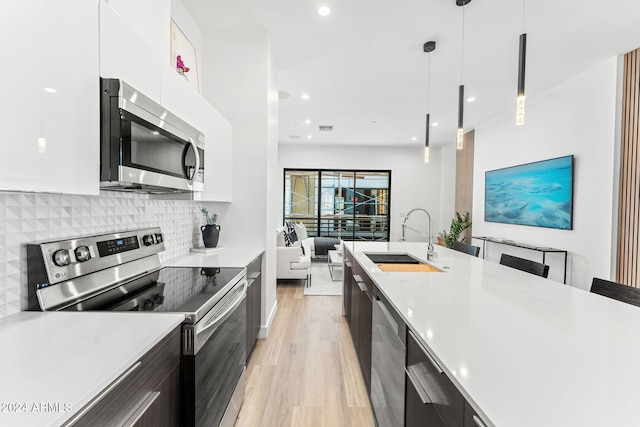 kitchen featuring appliances with stainless steel finishes, a sink, light countertops, light wood-type flooring, and modern cabinets