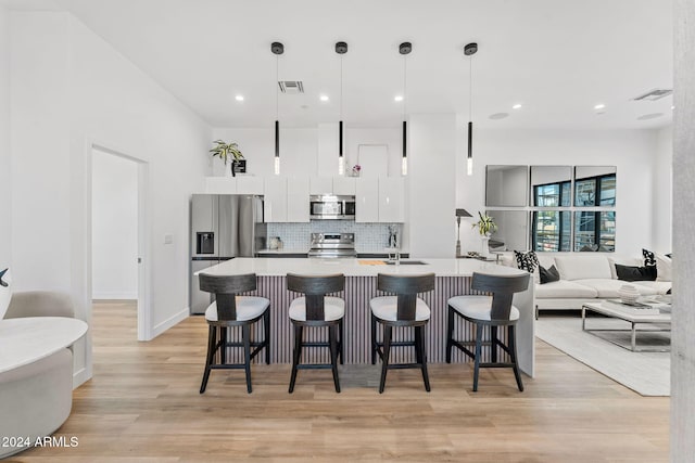 kitchen with white cabinets, stainless steel appliances, tasteful backsplash, and a kitchen breakfast bar