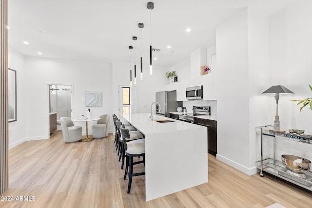 kitchen with a sink, a breakfast bar, stainless steel appliances, and light wood-style flooring