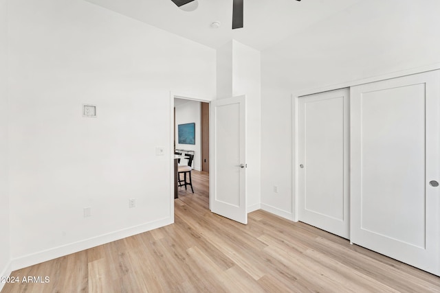 unfurnished bedroom with baseboards, a ceiling fan, a closet, and light wood-style flooring