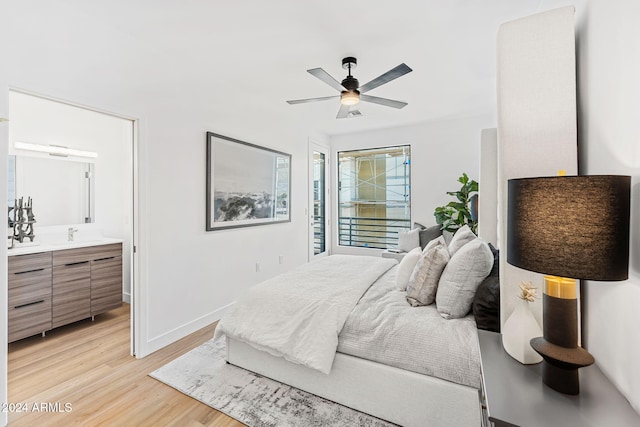 bedroom with connected bathroom, ceiling fan, a sink, light wood-style floors, and baseboards