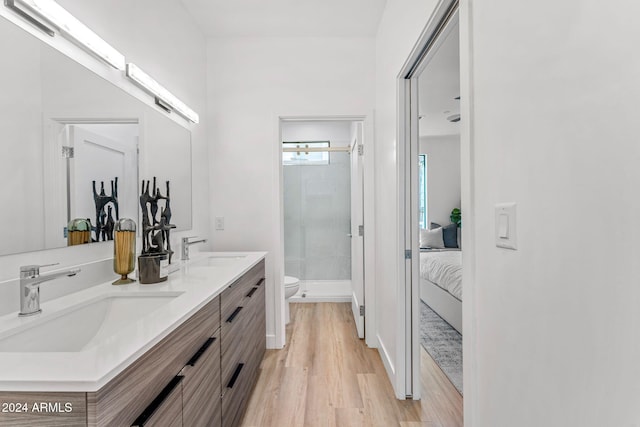 ensuite bathroom with toilet, a sink, ensuite bathroom, and wood finished floors