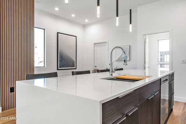 kitchen with pendant lighting, modern cabinets, light countertops, a sink, and light wood-style flooring