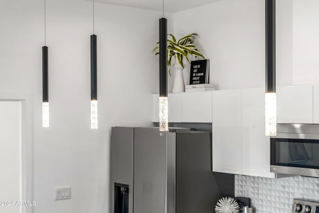 details featuring tasteful backsplash, stainless steel appliances, and white cabinets