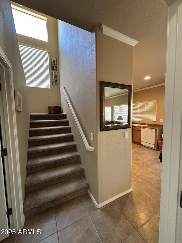 stairs featuring sink, tile patterned floors, and crown molding