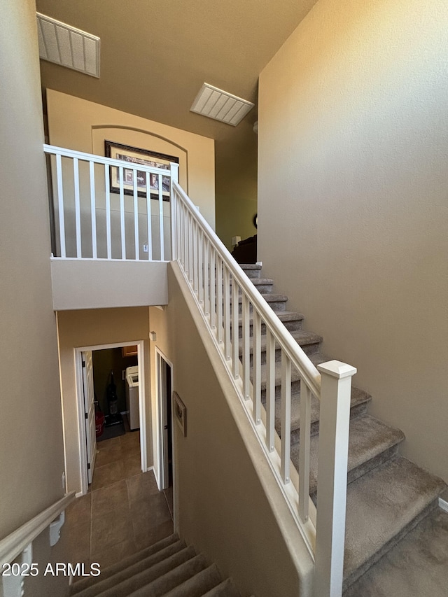 staircase featuring tile patterned floors and a high ceiling